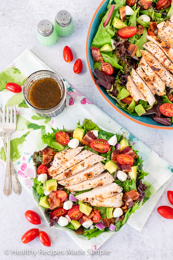 Overhead shot of grilled chicken on a bed of spring mix and vegetables.