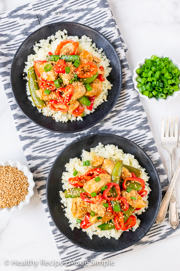 Plated chicken and vegetables on a bed of cauliflower rice.
