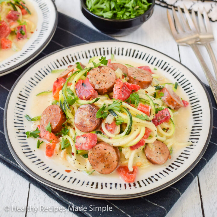 Square picture of a plate of zucchini alfredo with chicken sausage.