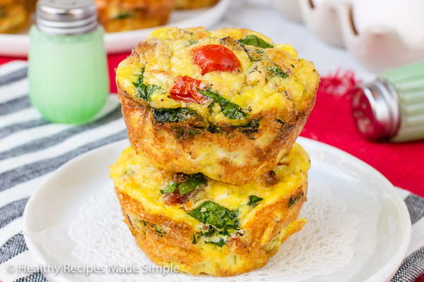 Rectangle picture of 2 keto egg muffin cups stacked together on a white plate.