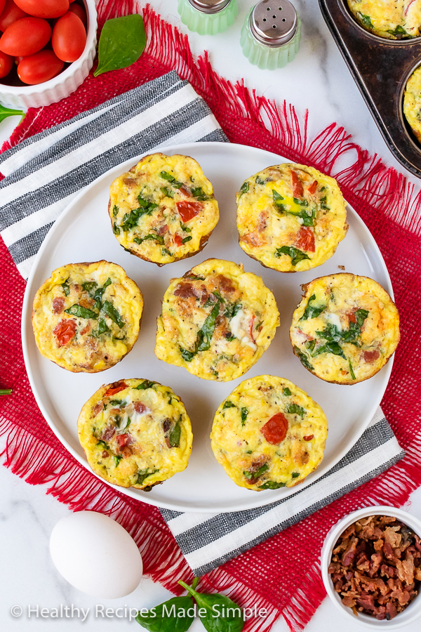 Overhead shot of 7 keto egg muffin cups on a white plate.