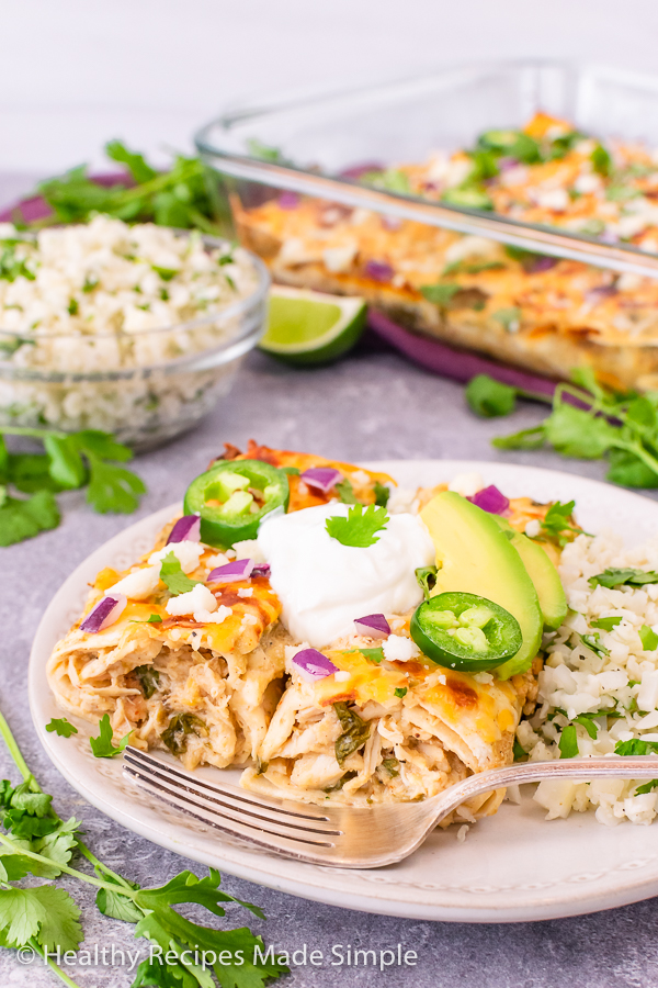 2 healthy white chicken enchiladas with cauliflower rice in the background.