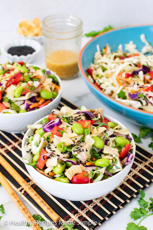 2 small bowls of cabbage salad with a big bowl in the background.