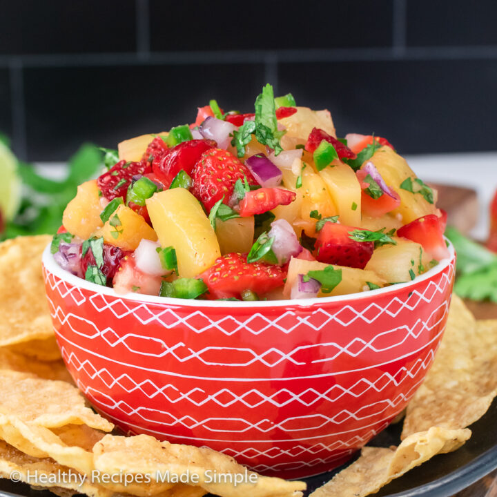 A red bowl full of strawberry pineapple salsa.
