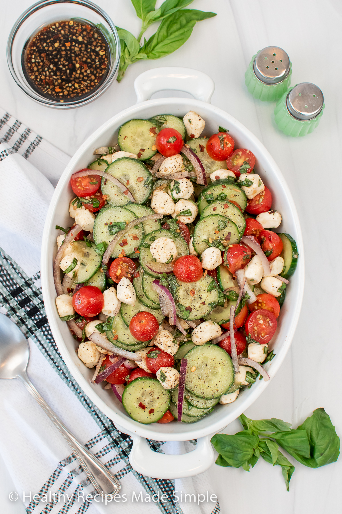 A large oval dish filled with cucumber tomato mozzarella salad.