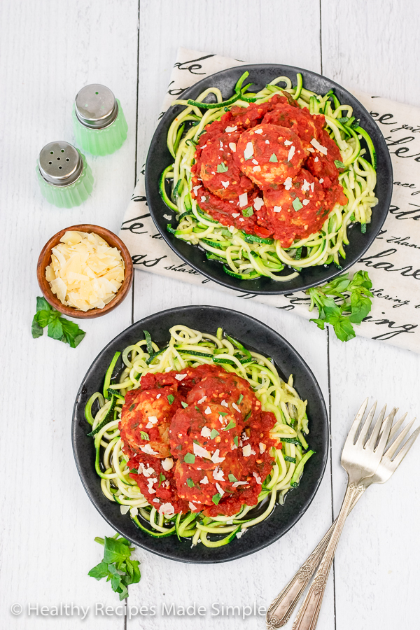 2 plates of zucchini noodles, tomato sauce and meatballs.