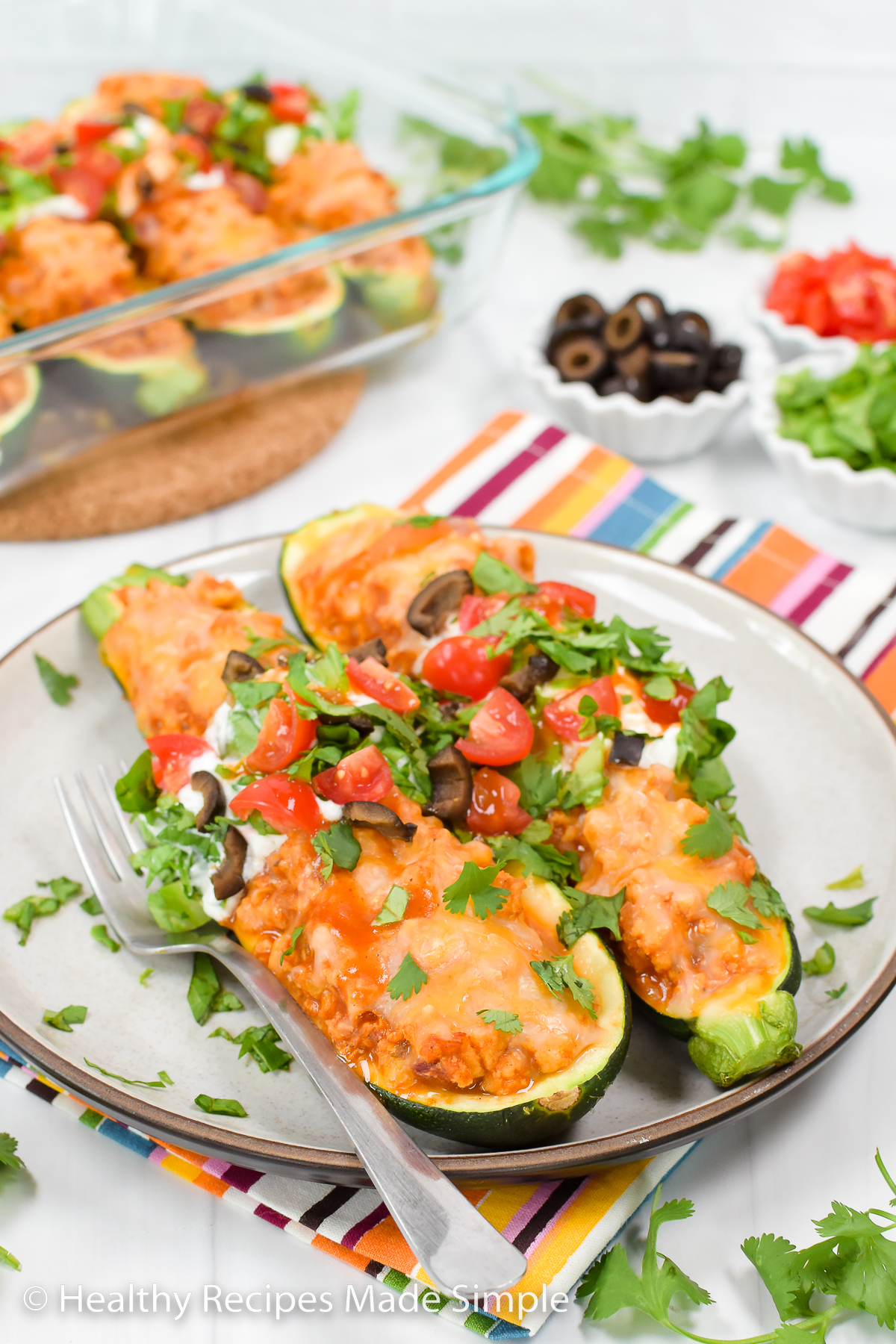 A plate of taco zucchini boats with a glass pan in the background.