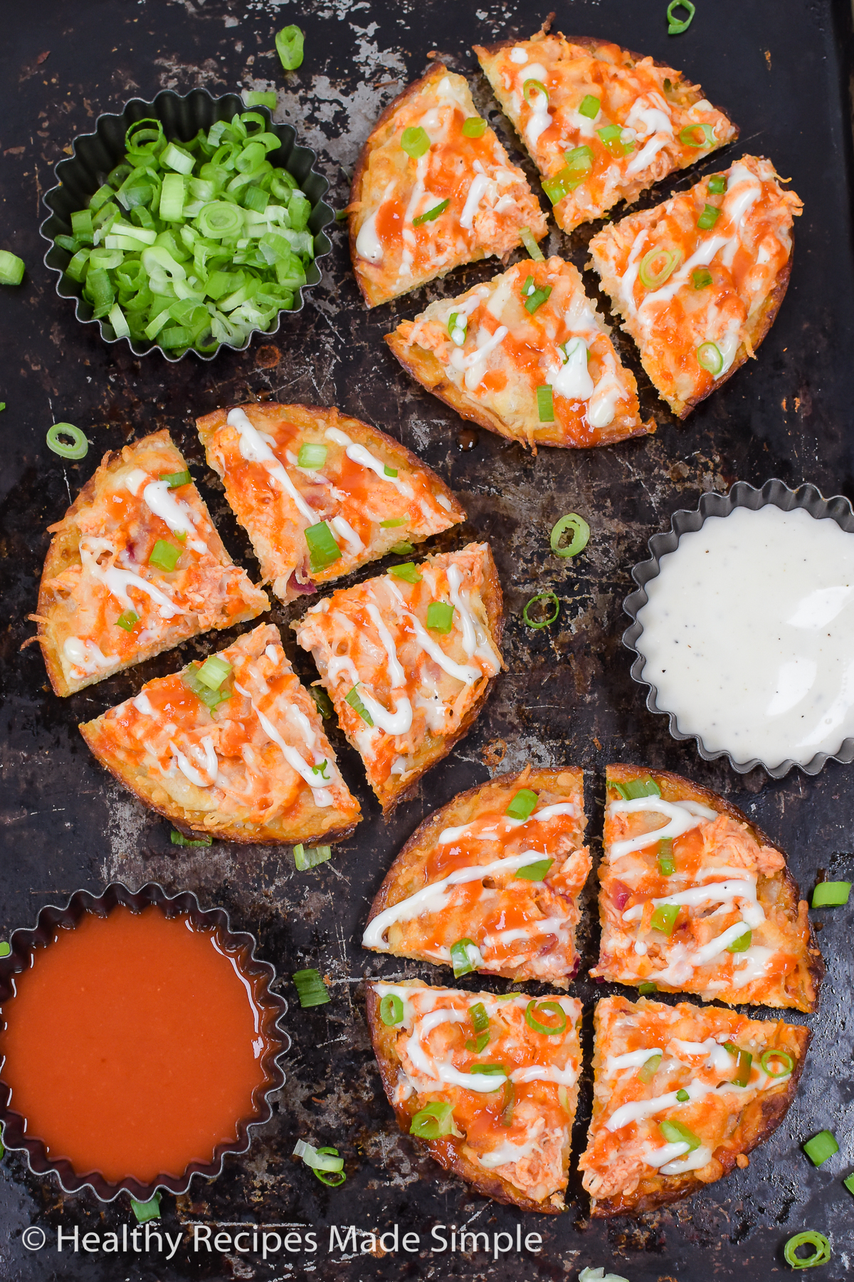 3 buffalo chicken pizzas with cups of green onion, ranch, and hot sauce.