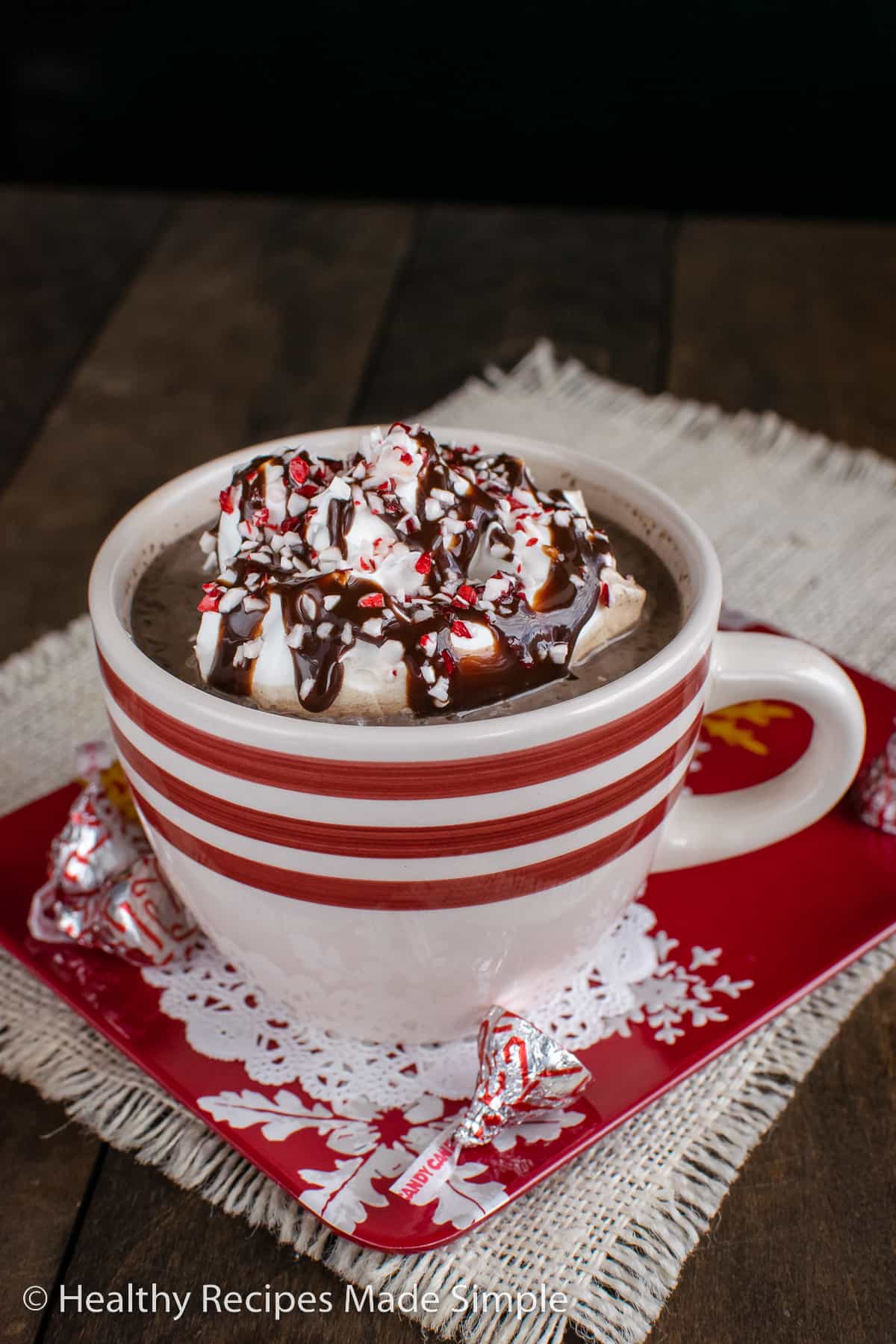 A mug of hot chocolate topped with whipped cream and chocolate syrup.