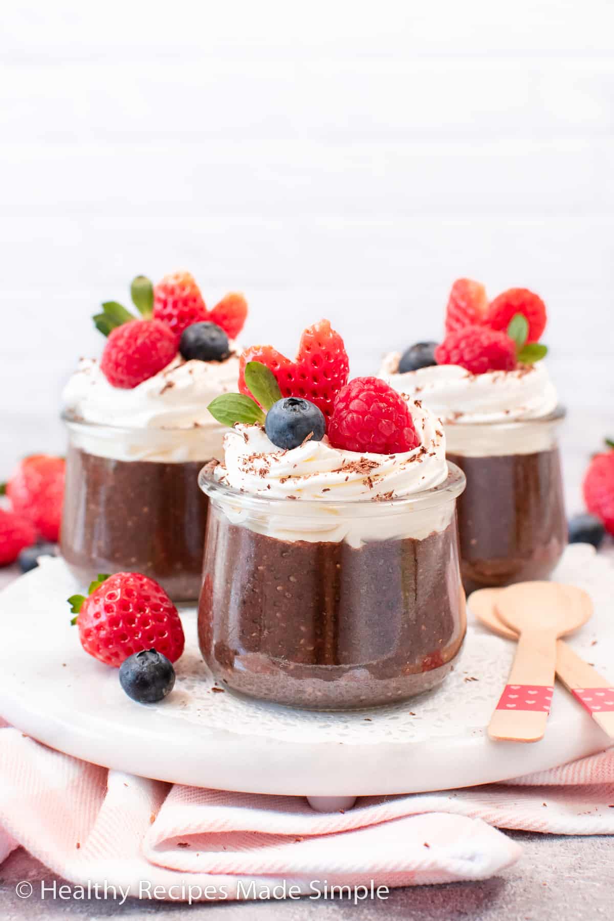 A clear jar of chocolate chia pudding topped with  whipped cream and fruit.