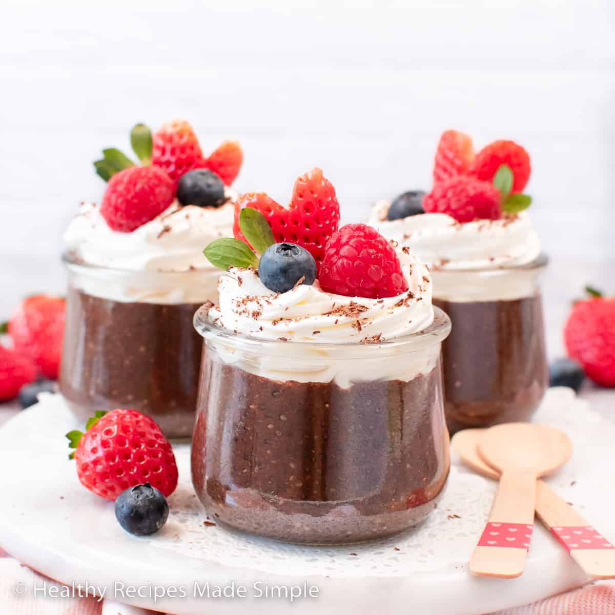 A clear jar of chocolate chia pudding topped with whipped cream and fruit.
