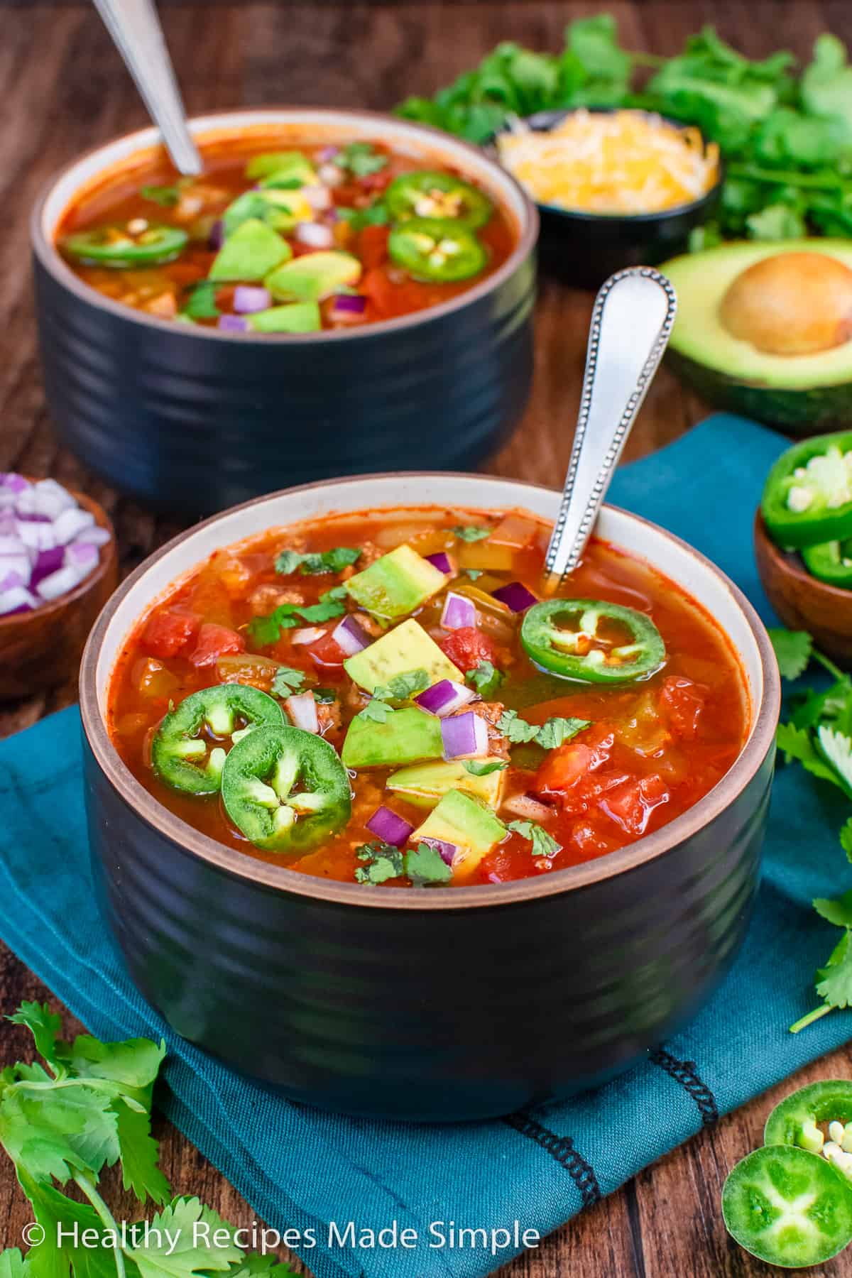 A bowl of no bean chili topped with avocado and jalapeño slices.