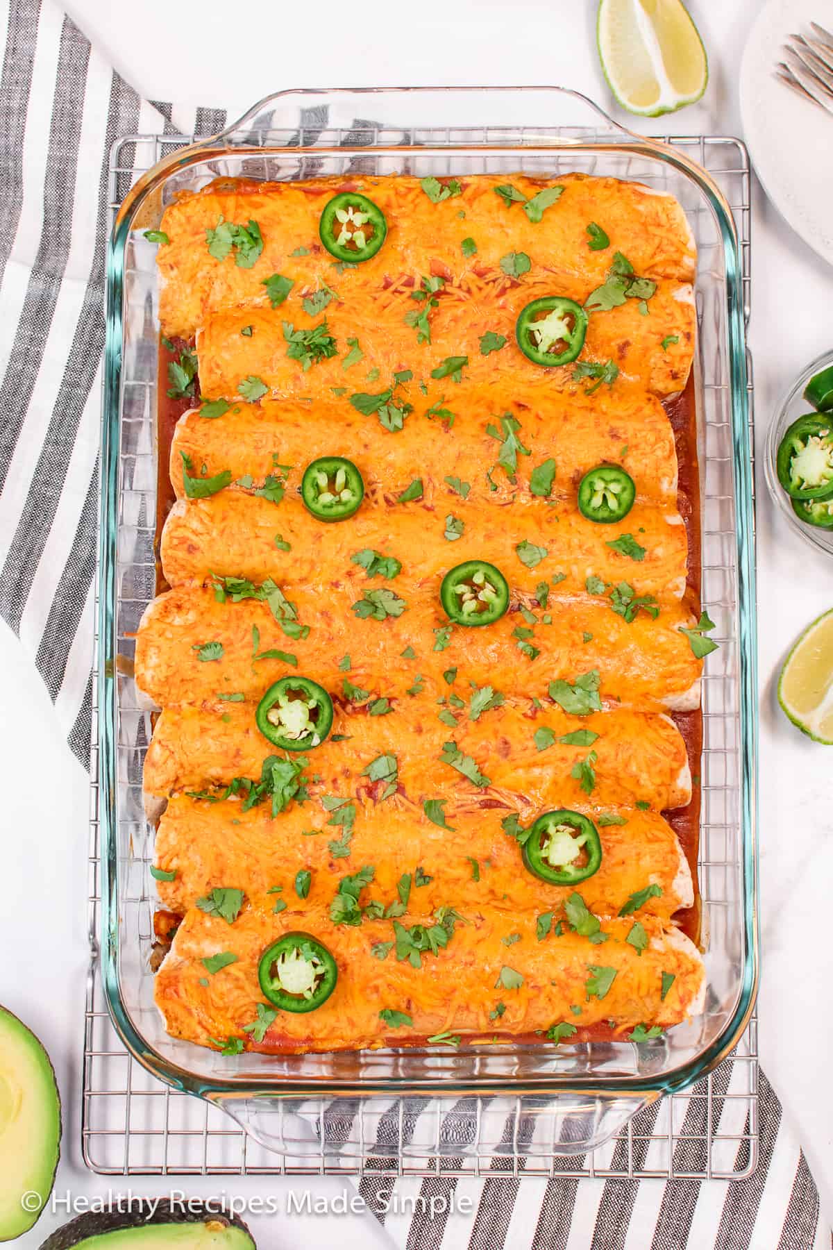 A full pan of low-carb beef enchiladas covered in cheese and topped with cilantro and jalapeño.