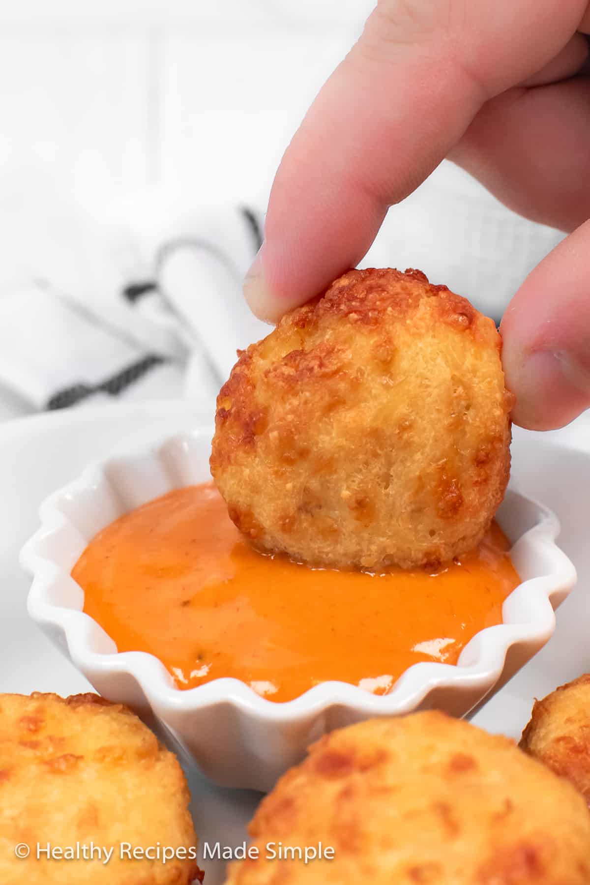 A crispy chicken nugget being dipped in sauce.