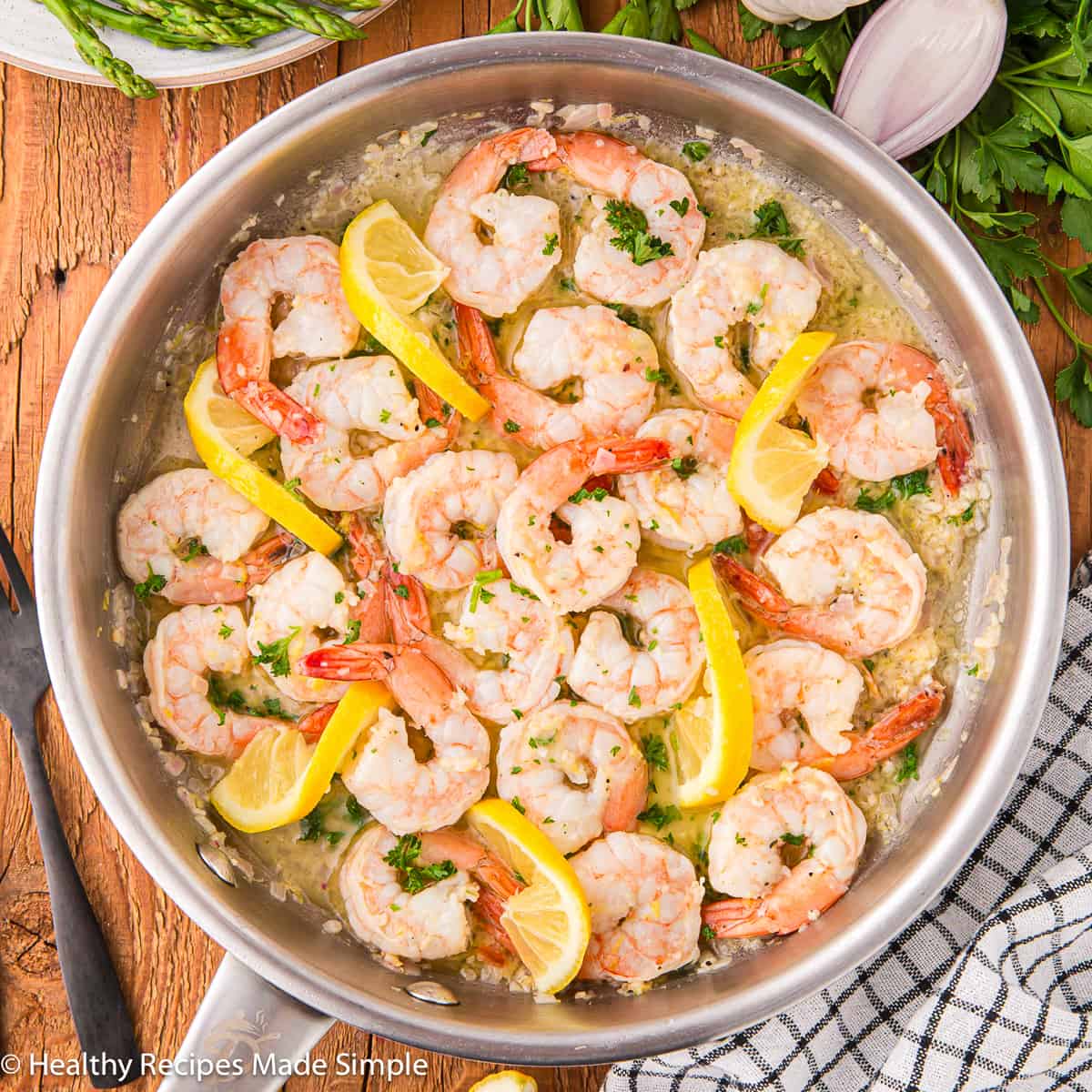 A skillet filled with cooked shrimp in garlic butter sauce.