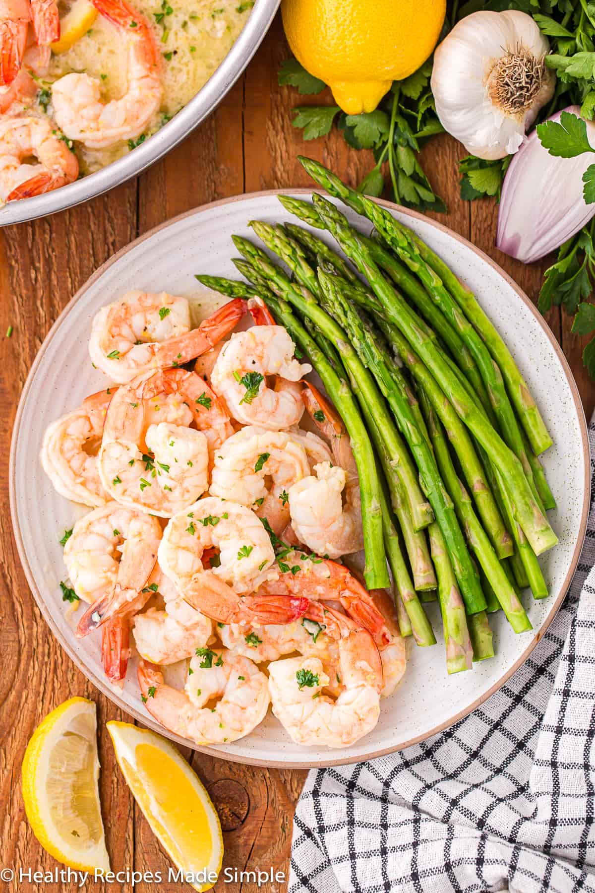 A plate with lemon garlic shrimp and asparagus on it.
