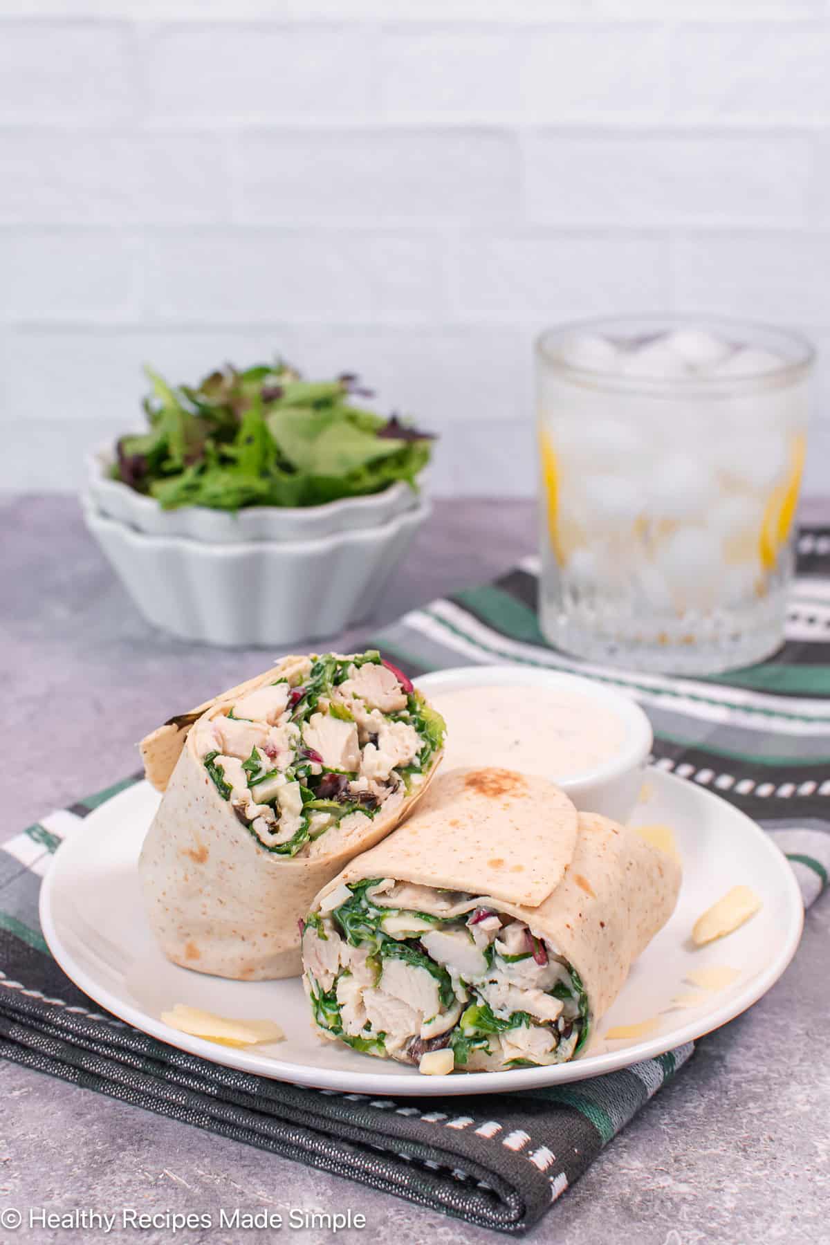 Two halves of a chicken wrap placed on a plate.