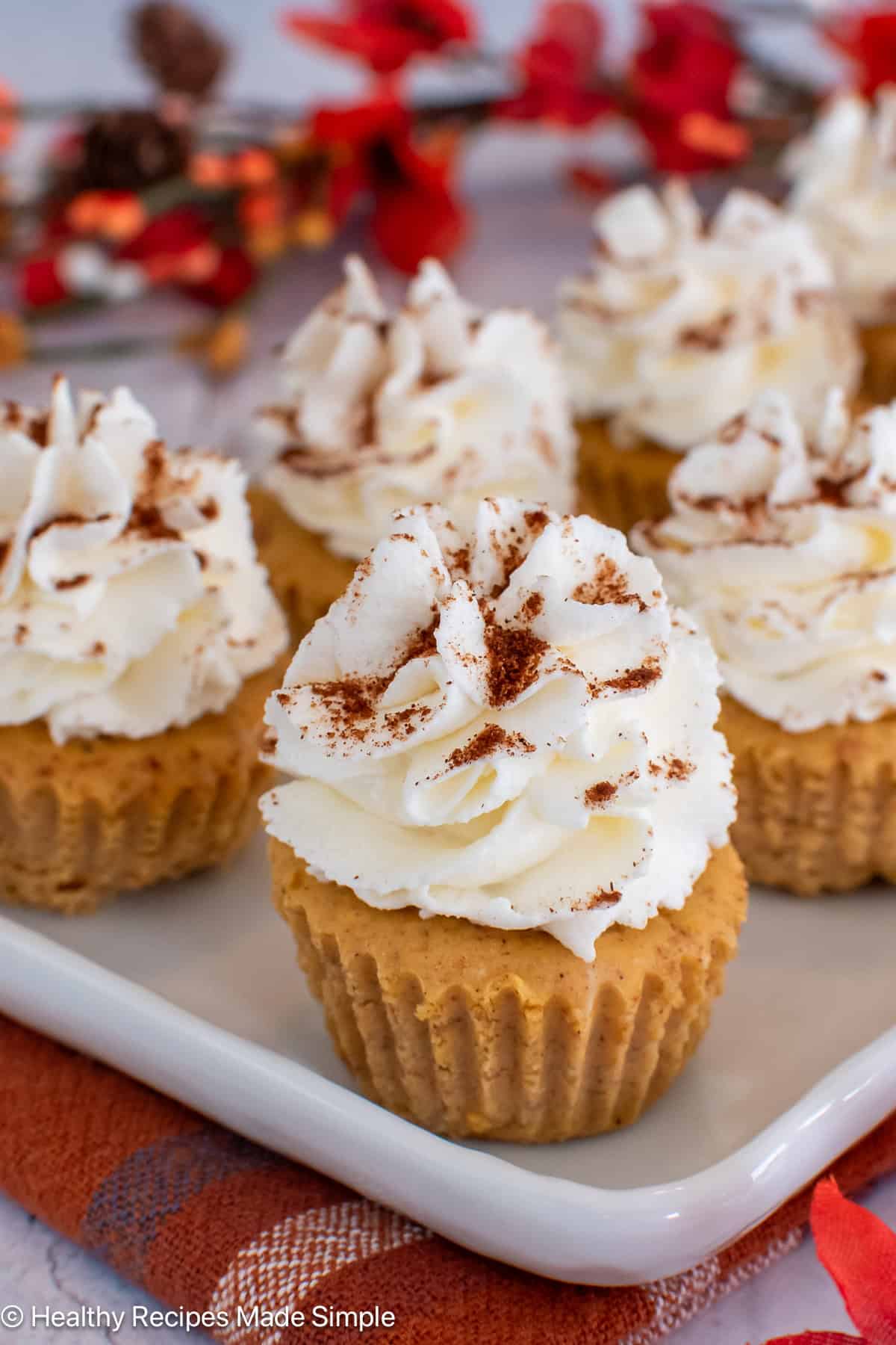 Mini cheesecakes with whipped topping on a white plate.