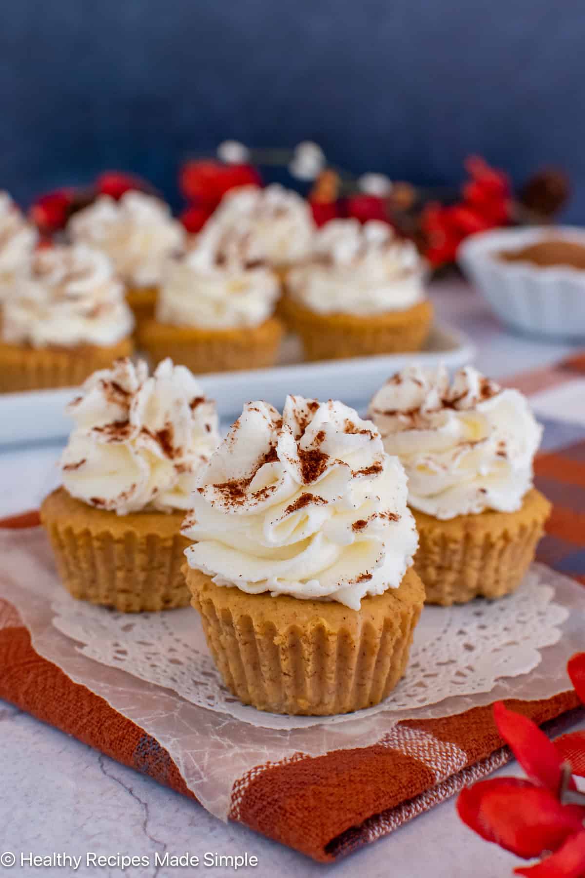 Three mini crustless pumpkin cheesecakes on a white paper.