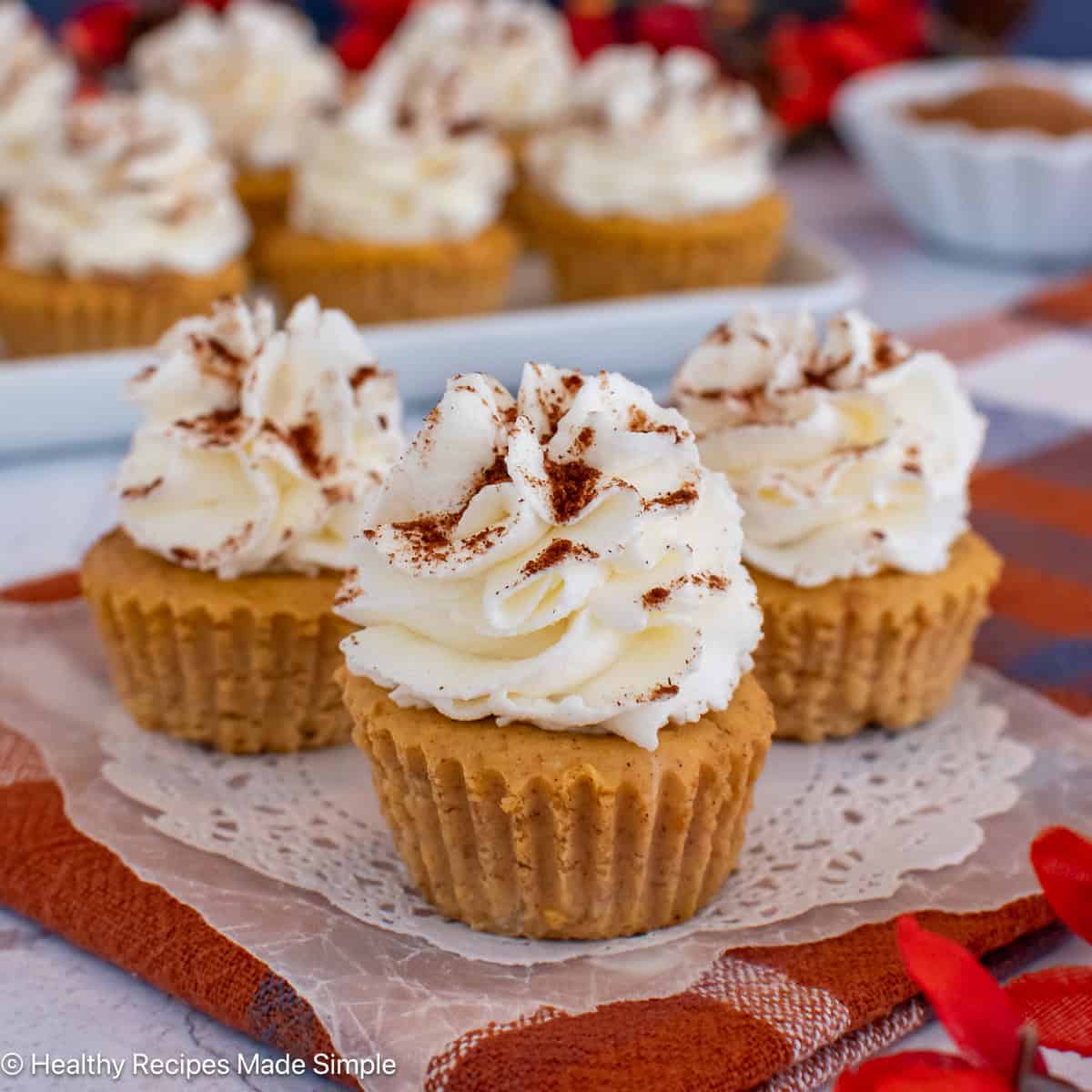 Three mini crustless pumpkin cheesecakes on a white paper.